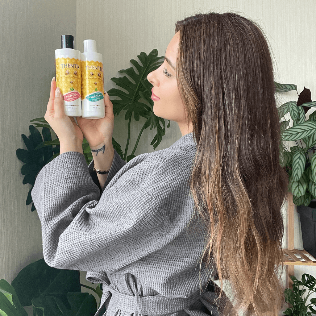 Woman looking at and admiring Thentix shampoo and hair conditioner with amazingly soft hair.