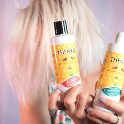 Thentix shampoo and hair conditioner being held by a woman who used them to care for their colored hair.