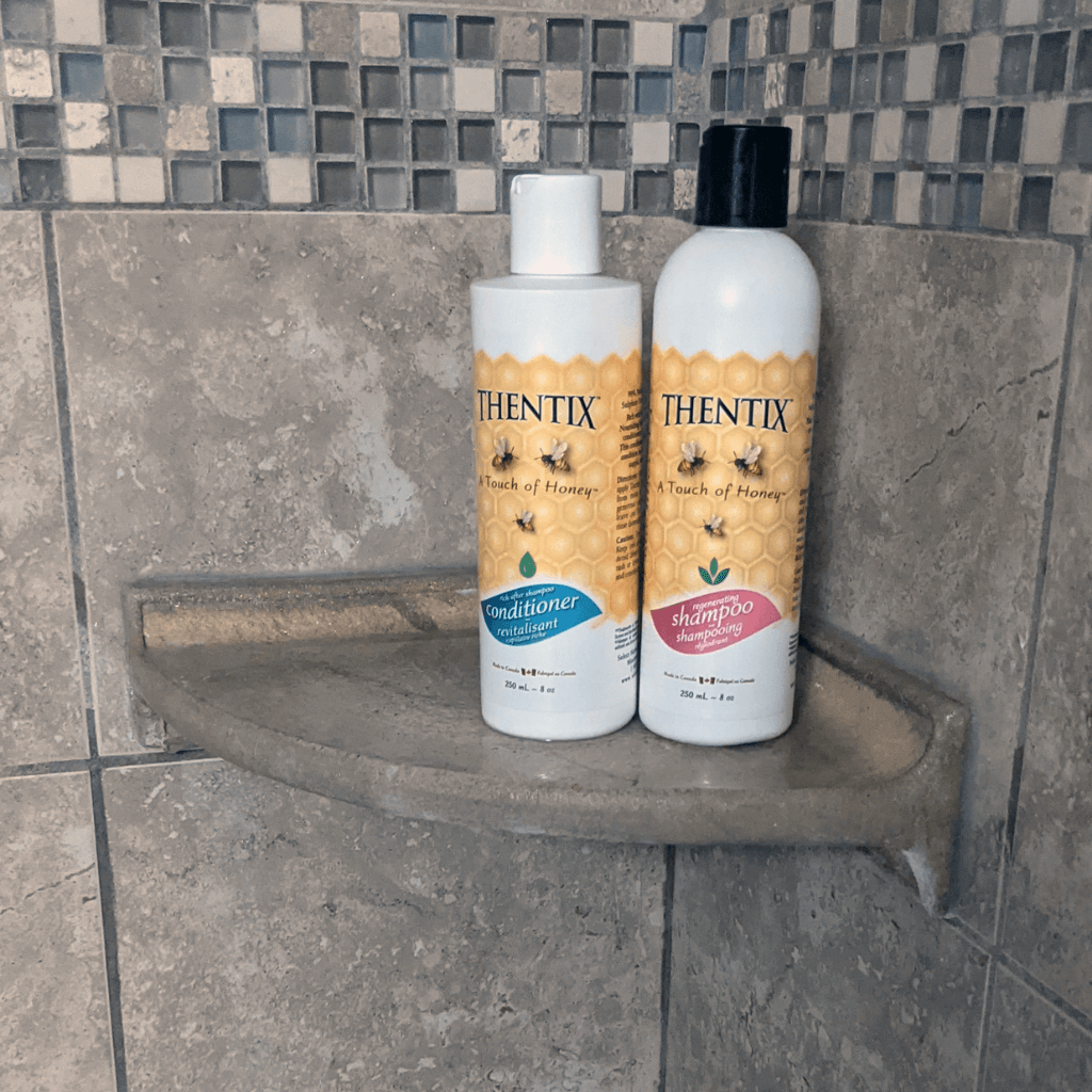 Thentix natural shampoo and hair conditioner on a shelf in a shower. The best hair care products to take care of your hair naturally.