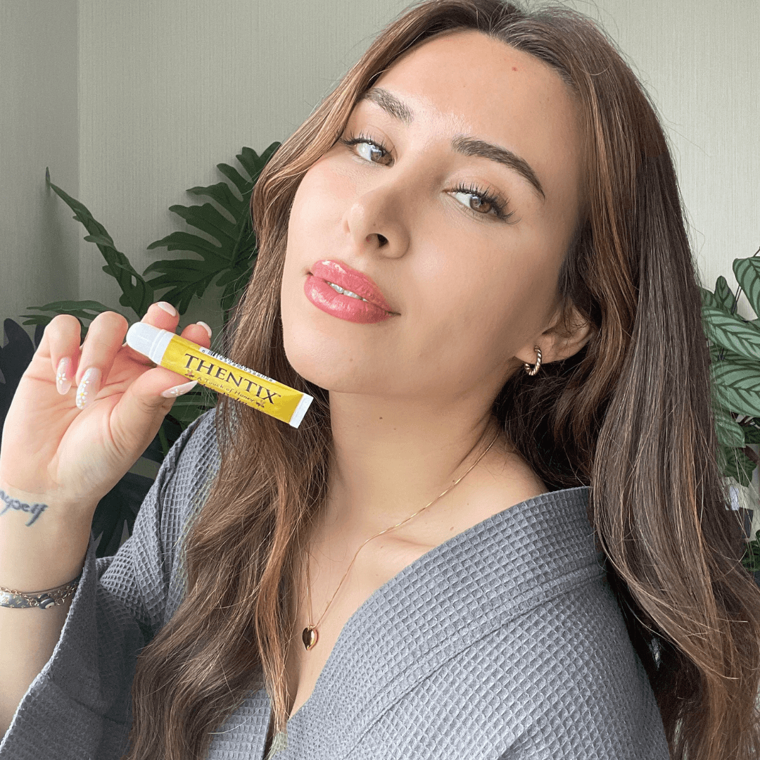 Thentix lip balm being held by a beautiful woman with soft lips, highlighting it as the best lip balm for hydrating and soothing lips.